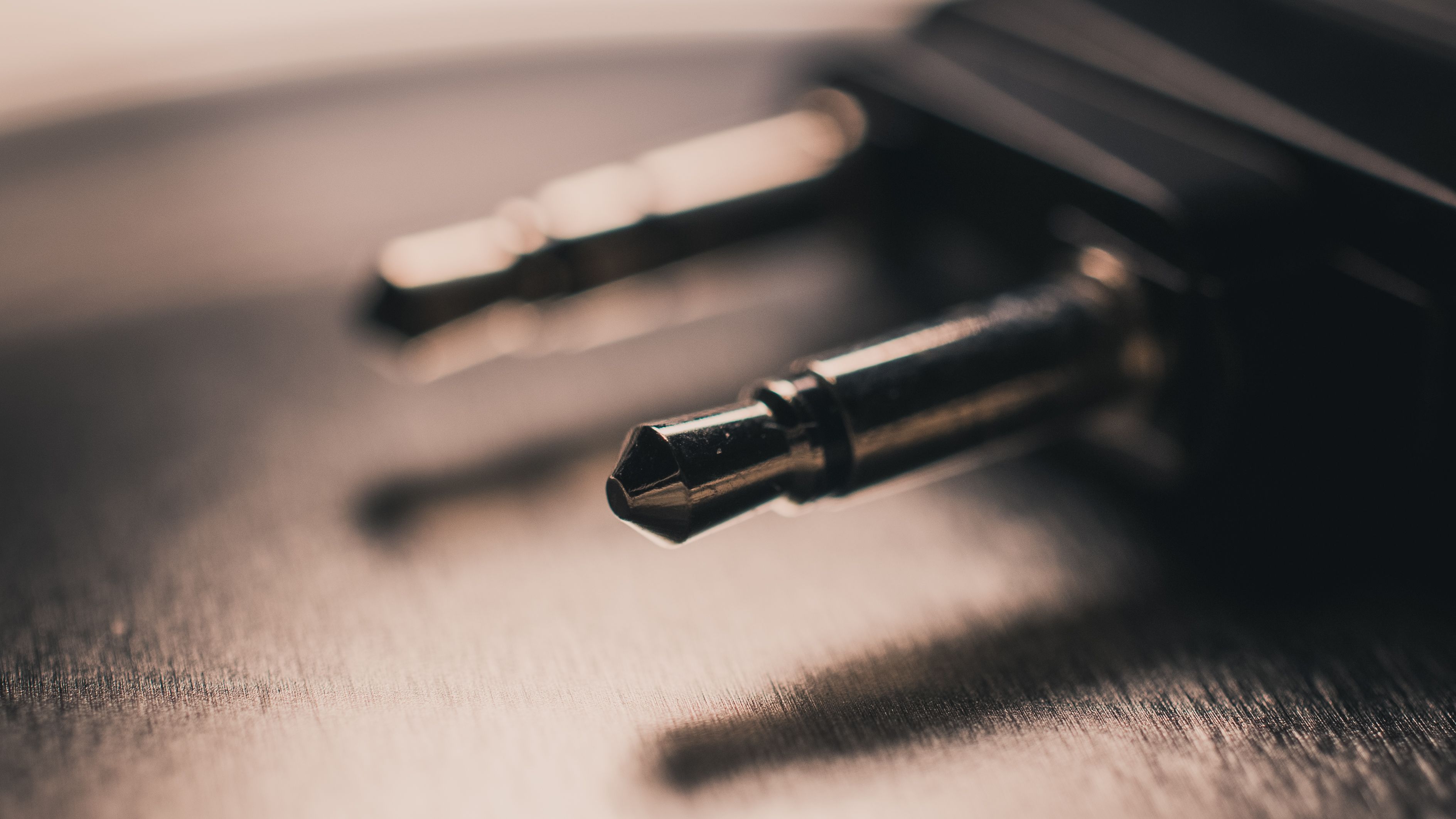 Macro close-up of a metallic audio jack placed on a brushed metal surface, emphasizing texture.