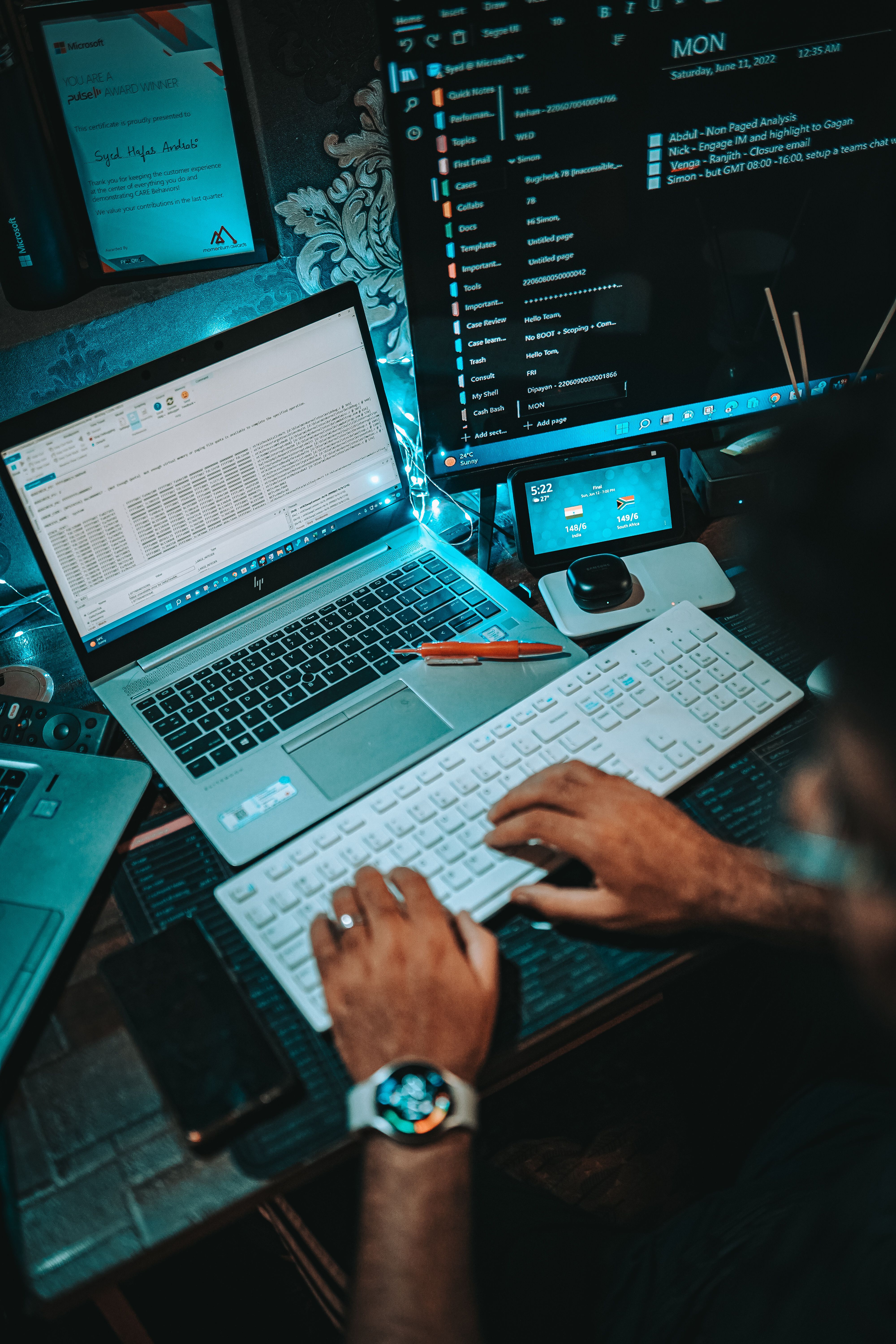 A person working on a dual-monitor setup with a laptop and keyboard in an office environment.