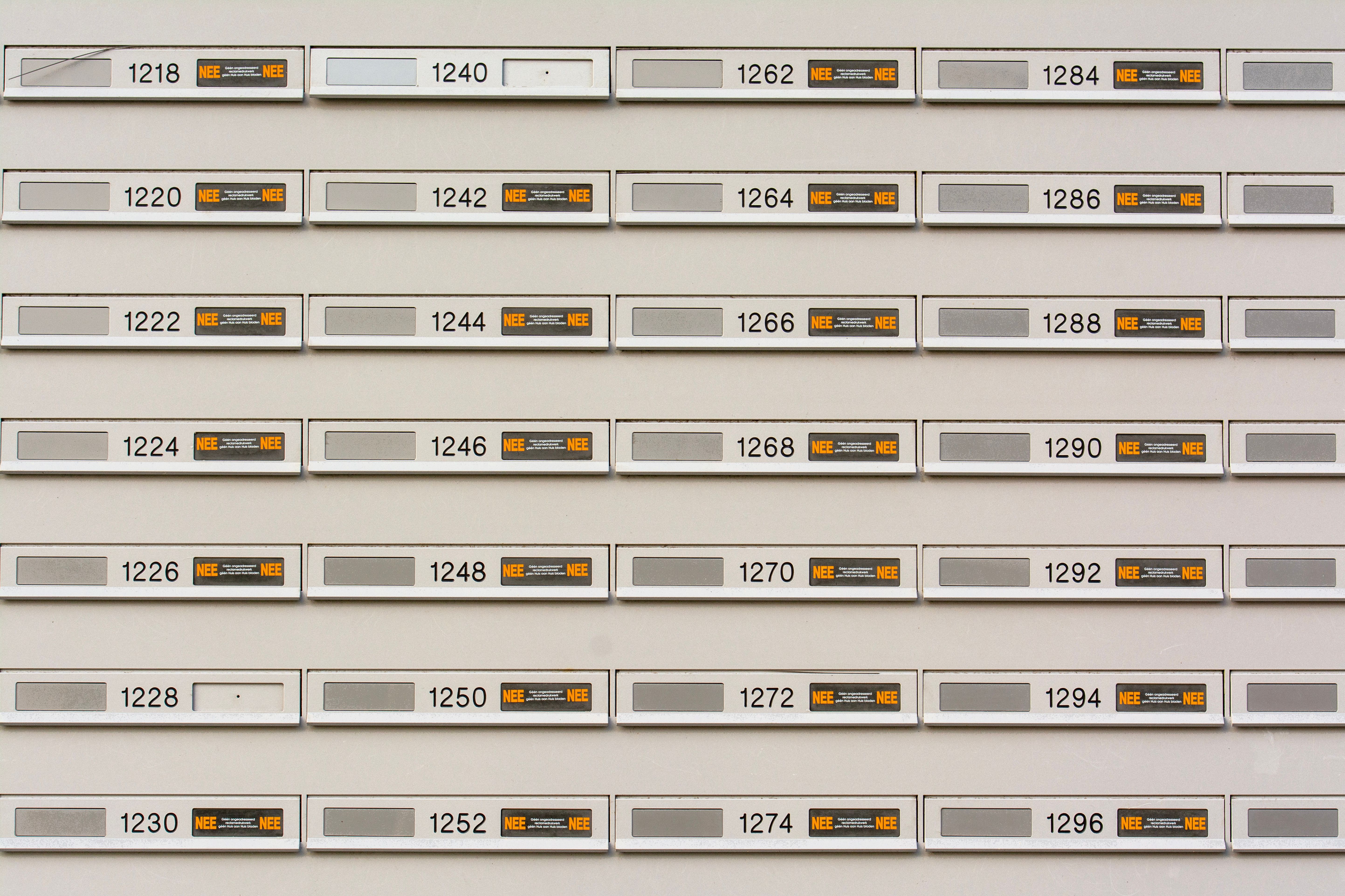 Row of modern mailboxes with numbers in an urban setting, featuring a pattern.