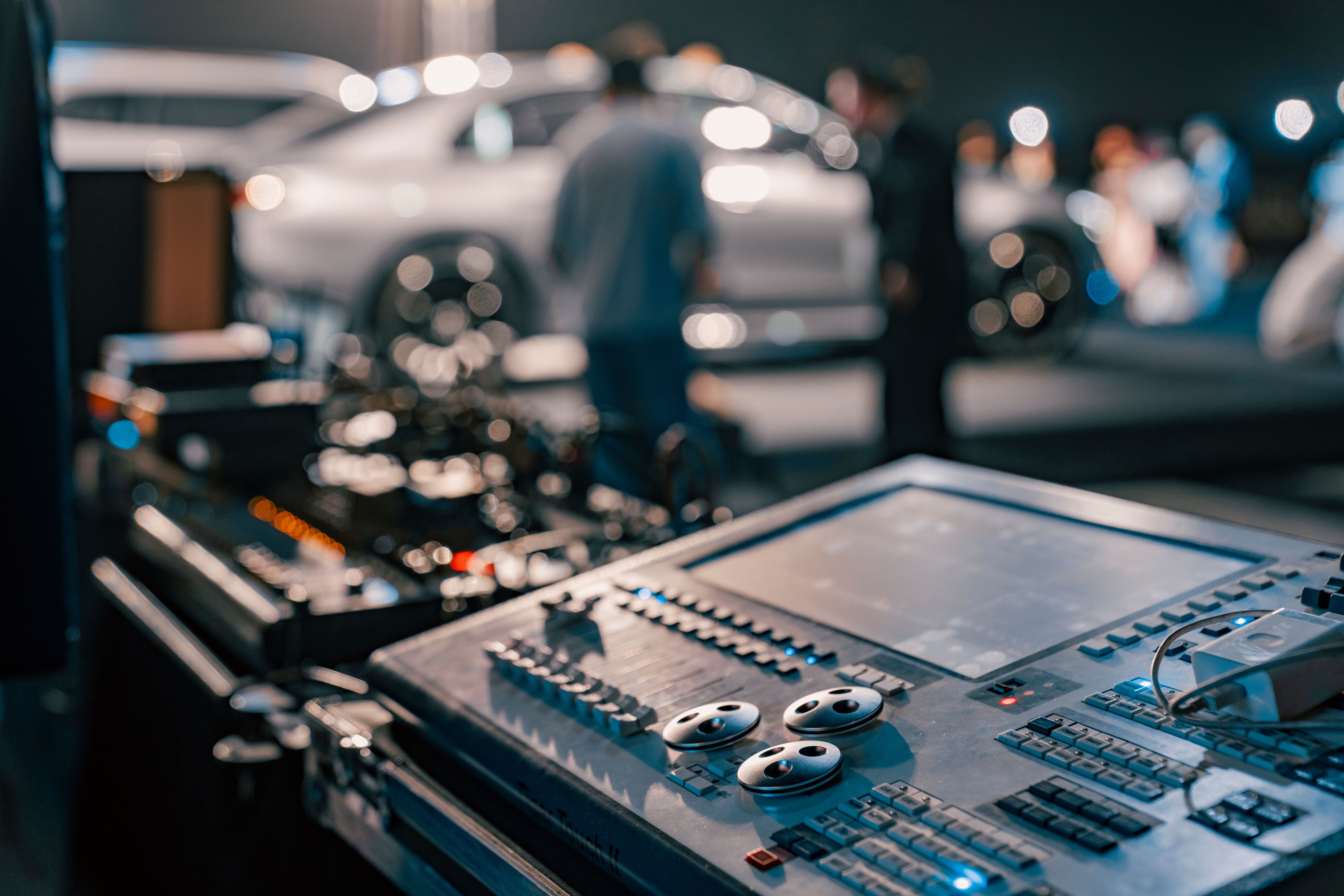 Close-up of a sound mixer at a lively indoor event with blurred people in the background.