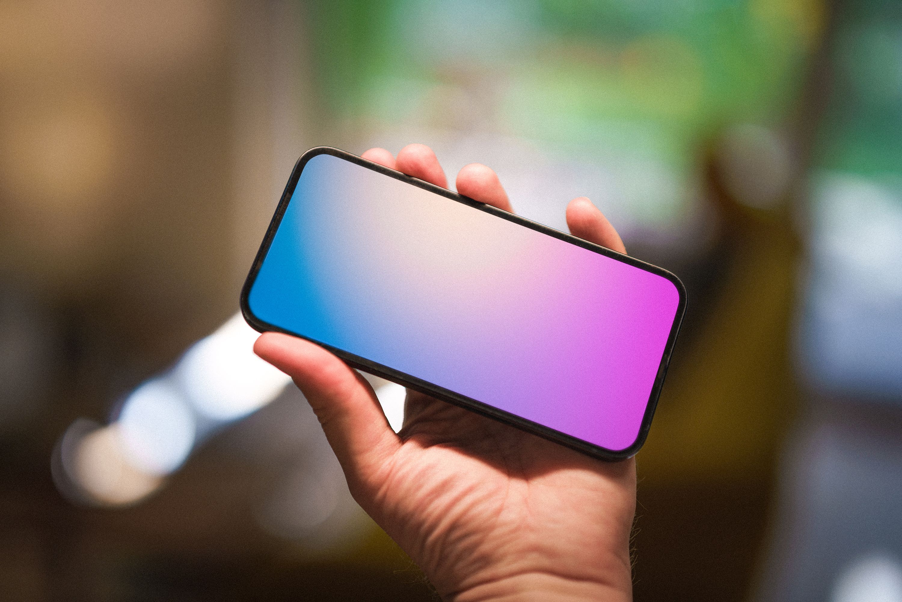 Close-up of a hand holding a smartphone displaying a gradient screen, symbolizing technology.