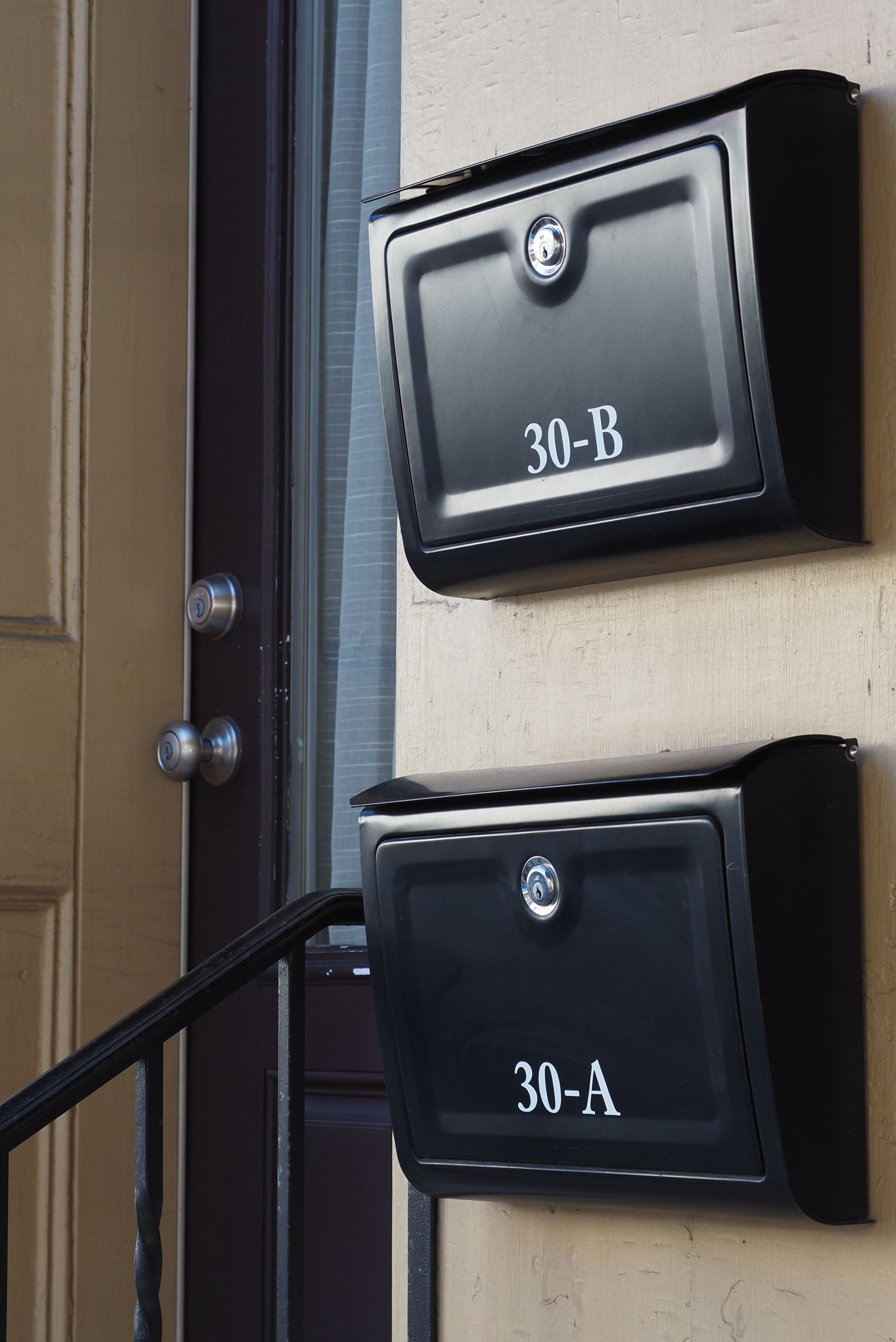 Two black mailboxes labeled 30-A and 30-B on a yellow-painted building in Doylestown, Pennsylvania.