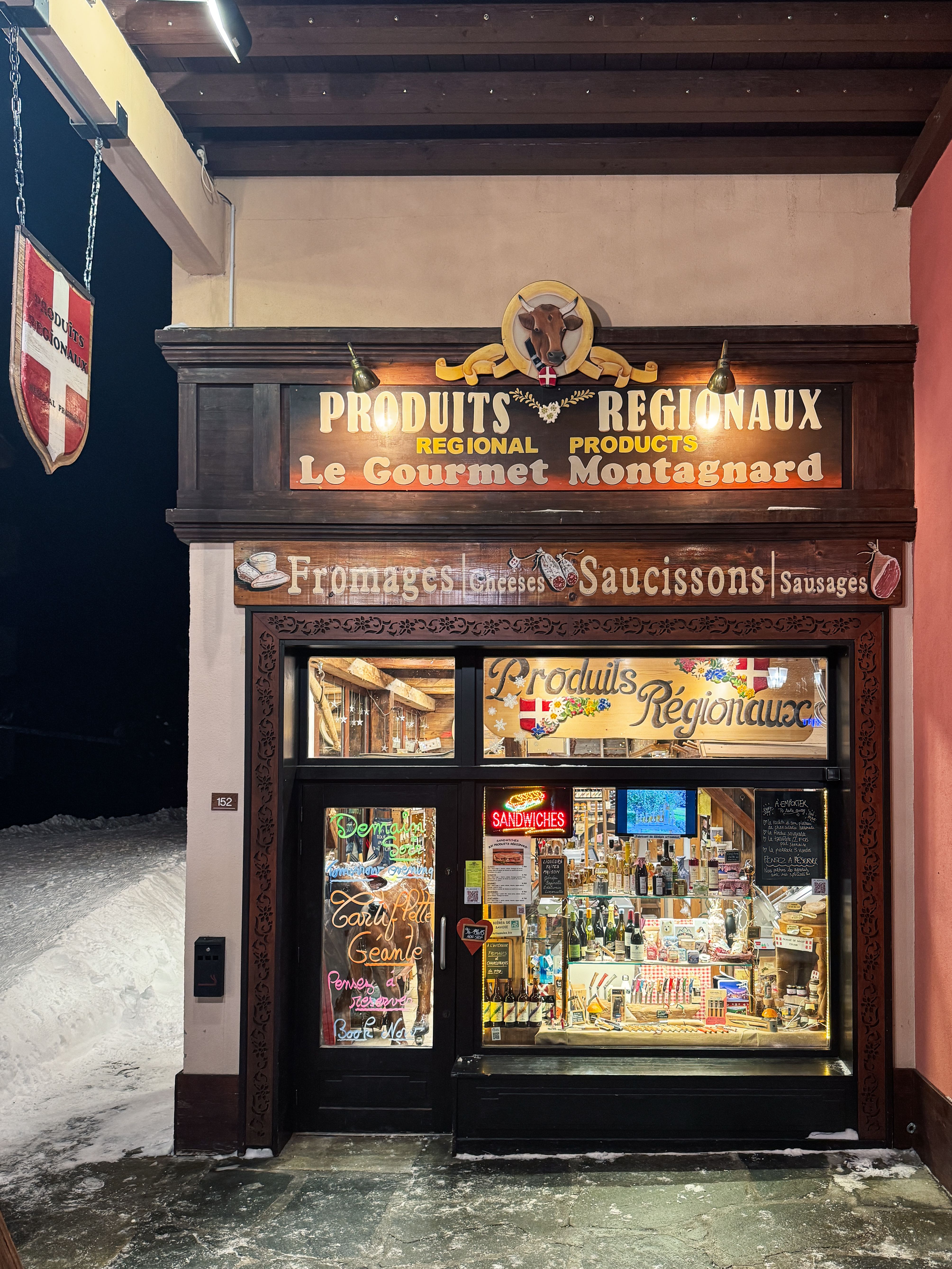 Night view of a traditional French grocery store, Le Gourmet Montagnard, in Les Arcs, France.
