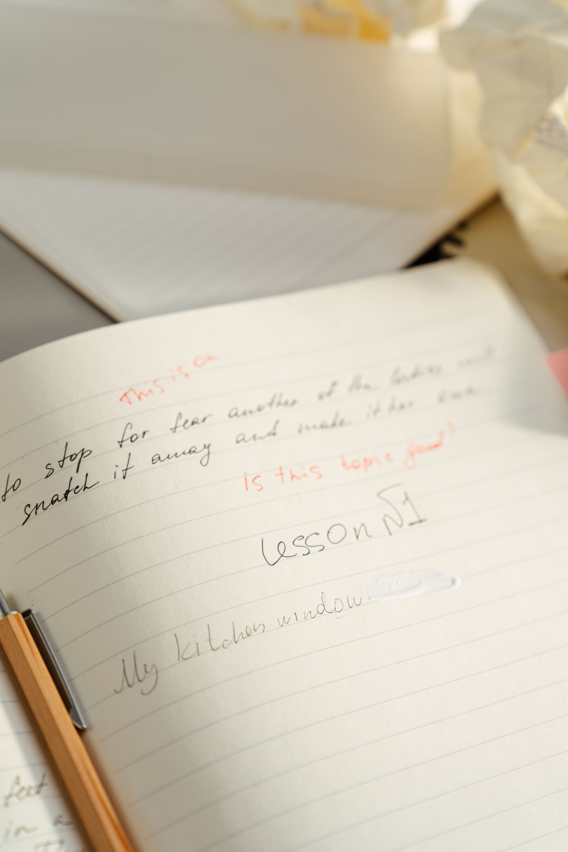 Open notebook with handwritten notes and a pen, softly lit from the side.
