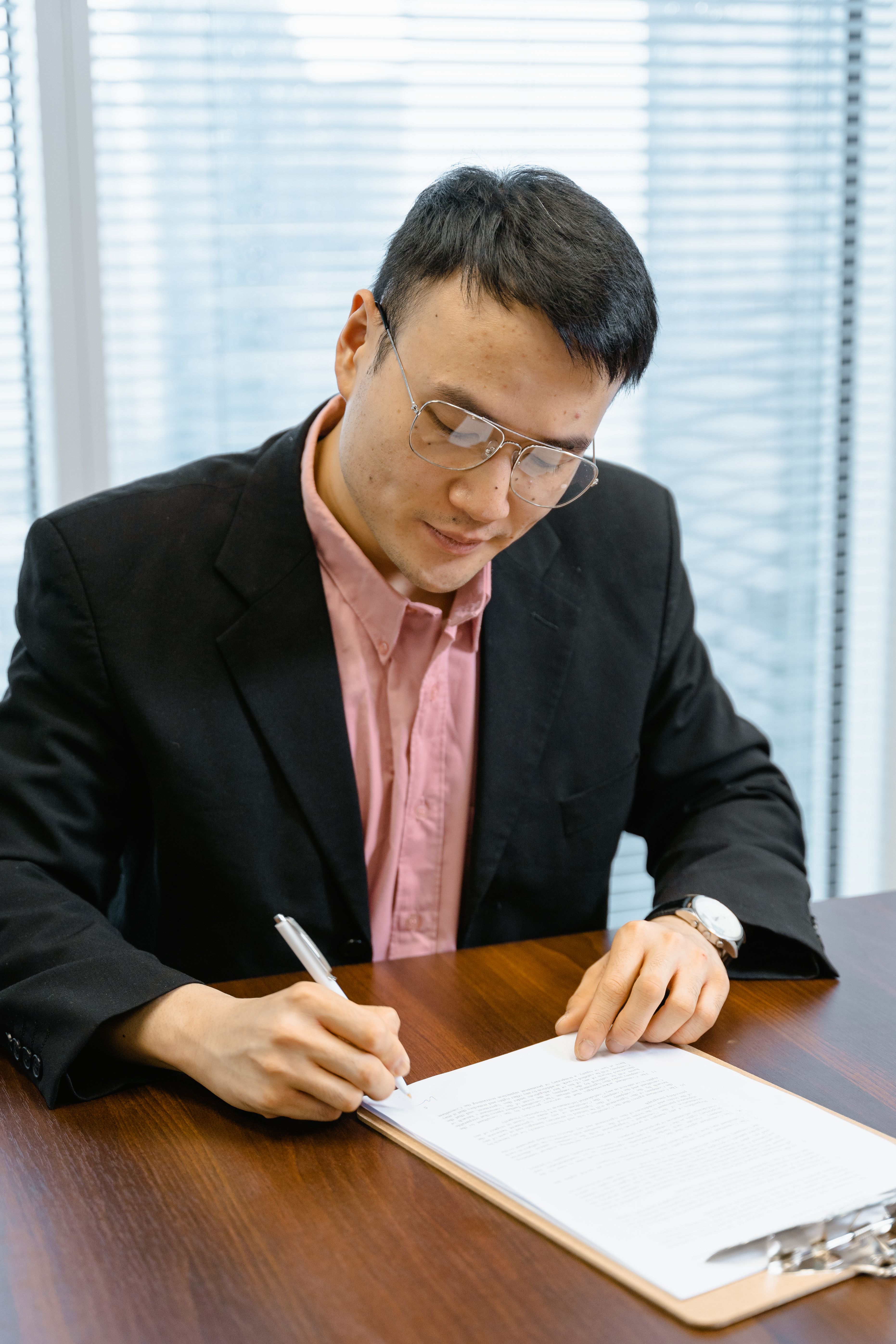 Professional man in business attire signing papers at an office desk.