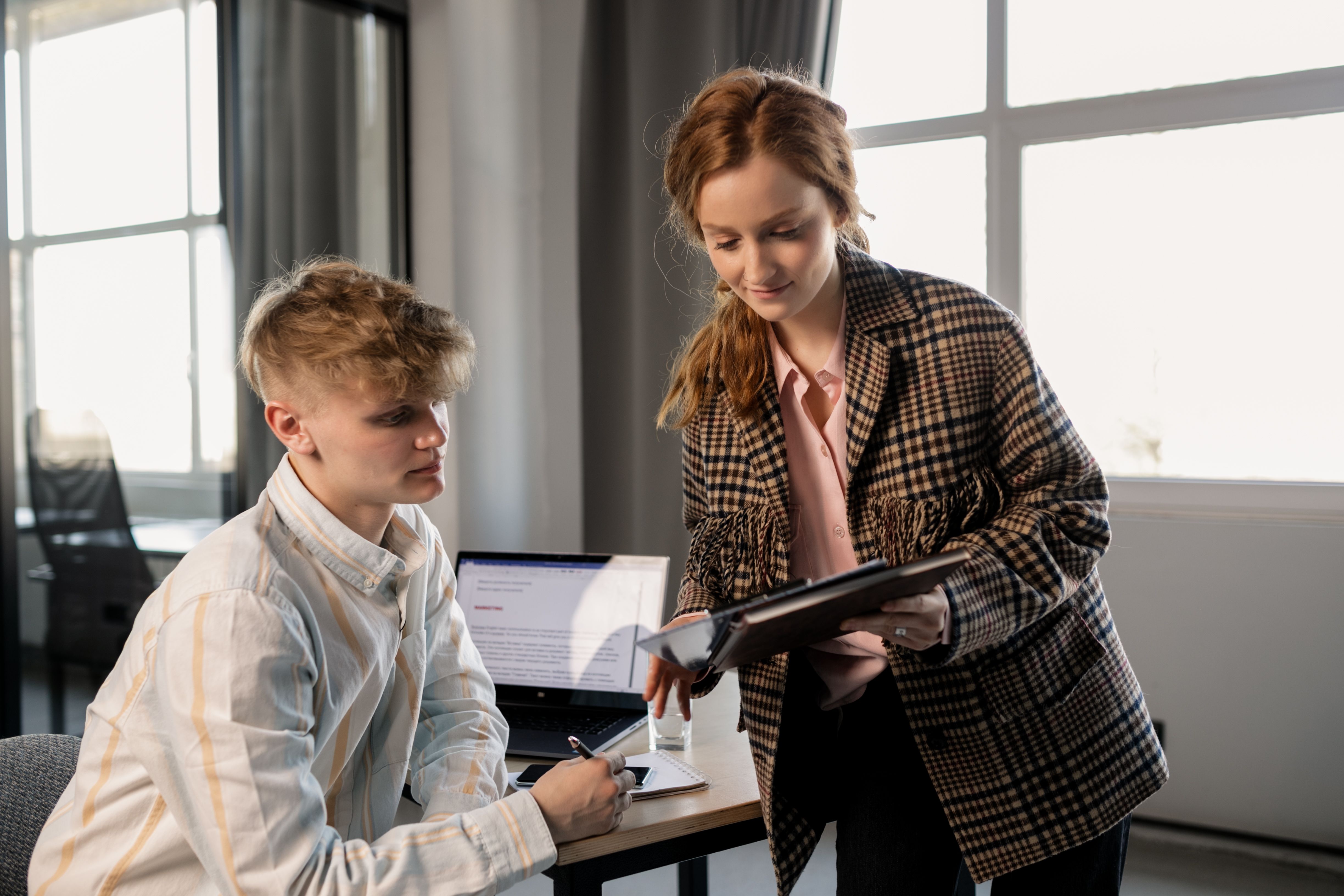 Two young professionals collaborating in a modern office environment, focusing on planning and teamwork.