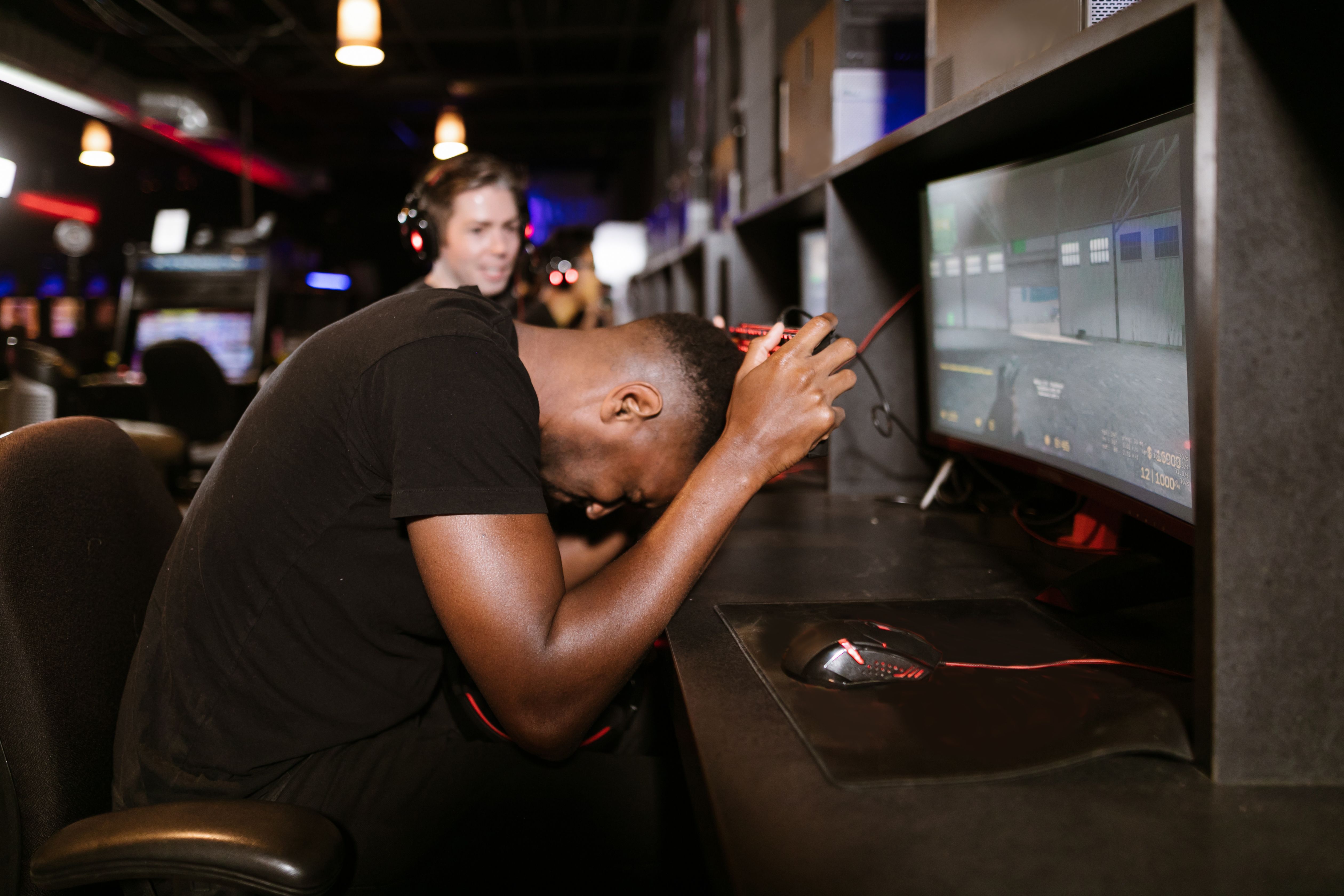 An adult male gamer shows frustration while playing a computer game in an esports arena.